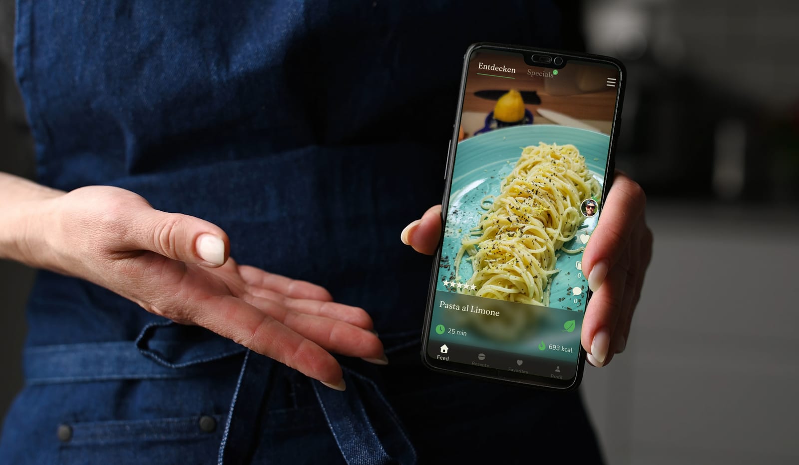 Eine Köchin hält ein Smartphone mit einem Rezept in der Royal-Food-Club-App entgegen